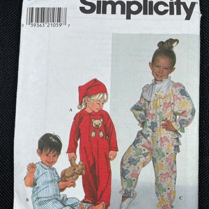 Könnte beinhalten: Simplicity Schnittmuster Nummer 7918 für Kinderpyjamas. Das Schnittmuster umfasst drei verschiedene Stile: einen roten Pyjama mit einem Bären-Applikationen, einen blau-weiß gestreiften Pyjama und einen mehrfarbigen Pyjama mit Rüschenbesatz.