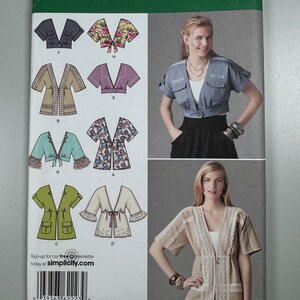 May include: A sewing pattern for a women's top with a V-neckline and short sleeves. The pattern includes five different styles, with variations in the neckline, sleeves, and fabric. The pattern is for sizes UK 14, 16, 18, 20, and 22, and is from Simplicity.