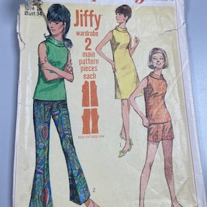Könnte beinhalten: Vintage Simplicity Schnittmuster Nummer 7021 für eine Jiffy-Garderobe mit zwei Hauptteilen. Das Schnittmuster enthält drei verschiedene Looks: ein grünes ärmelloses Oberteil mit Schlaghose, ein gelbes ärmelloses Kleid und ein ärmelloses oranges Oberteil mit Shorts. Das Schnittmuster ist mit "easy-cut easy-sew" gekennzeichnet.