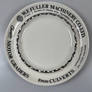 May include: A white plate with a corrugated silver rim and black text. The text reads "W.F. FULLER MACHINERY CO. LTD." and "Champion Motor Graders." The plate also says "Fulco Culverts" and "Corrugated Steel All Types and Sizes."