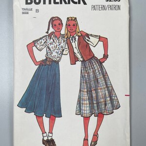 May include: A vintage sewing pattern for two skirts, one with a plaid print and the other with a solid blue colour. The pattern is from Quick & Easy Butterick and has the number 6449. The pattern is for size B.