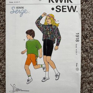 Może przedstawiać: Vintage wzór szycia Kwik Sew, numer wzoru 1918, z ilustracjami odzieży dziecięcej. Okładka przedstawia dziewczynkę w topie i szortach we wzory oraz chłopca w zielonej koszuli i pomarańczowych szortach. Rozmiary wzoru to 4-5-6-7.