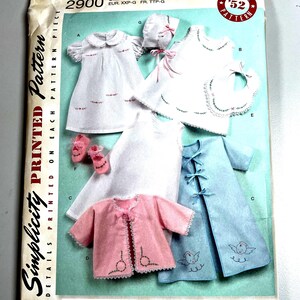 May include: Vintage Simplicity sewing pattern number 2900 for a baby's outfit. The pattern includes a dress, bonnet, bib, jacket, and pants. The pattern is printed on a blue background with white text and illustrations.