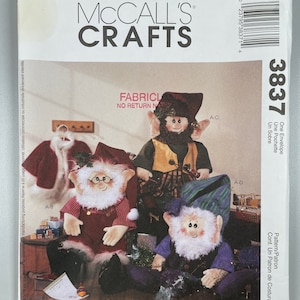 Może przedstawiać: Wzór szycia dla trzech różnych lalek gnomów. Wzór pochodzi od Faye Wine i jest z McCall's Crafts. Gnomy noszą ubrania i czapki w różnych kolorach. Wzór jest przeznaczony wyłącznie do użytku domowego.