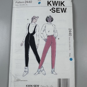 May include: A Kwik Sew pattern envelope for pattern 2440, featuring illustrations of two outfits: a black jumpsuit with a turtleneck and a pair of pink stirrup pants with a turtleneck. The envelope includes text labels A and B, sizes XS-S-M-L-XL, and a barcode.