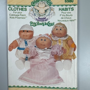 Könnte beinhalten: Ein Vintage Butterick-Schnittmuster für Cabbage Patch Kids Frühchen. Das Cover zeigt Illustrationen von drei Puppen in verschiedenen Outfits, mit Text wie "CLOTHES" und "HABITS". Die Schnittmusternummer ist 6980.