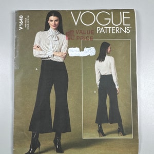 Puede incluir: Patrón de costura Vogue Patterns para un pantalón negro acampanado y una blusa blanca de lunares. El número del patrón es V1640. El patrón es para las tallas 16-18-20-12-14.