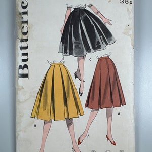 May include: Vintage sewing pattern for a skirt, featuring three different styles. The pattern is from Butterick and has the number 8793 printed on it. The skirt styles are black, yellow, and brown.
