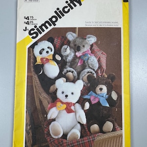 May include: Simplicity pattern envelope showing several teddy bear designs. The bears include a panda, koala, white bear, and brown bear, each with a heart-shaped accessory. The envelope has the text "Simplicity" and the number "6142".