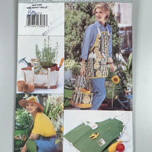 Puede incluir: Un patrón de costura para un delantal de jardinería con bolsillos y una bolsa de mano a juego. El patrón es de Butterick y es de talla única. El patrón muestra a una mujer usando el delantal y llevando la bolsa de mano.