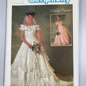 May include: Simplicity sewing pattern number 6766 size 8 for a wedding dress with a lace trim and a long train. The pattern is designed by Michele Piccione.