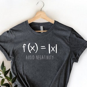 May include: A dark gray t-shirt with white text that reads "f(x) = |x| AVOID NEGATIVITY".