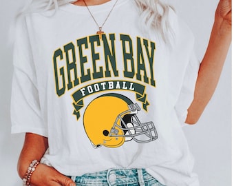 Puede incluir: Camiseta blanca con un gráfico verde y amarillo de un casco de fútbol y el texto "Green Bay Football".