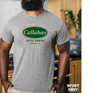 May include: Sport grey t-shirt featuring the text "Callahan Auto Parts" in a green and white oval design. The text "Sandusky, OH" is below the oval. The shirt is short-sleeved.