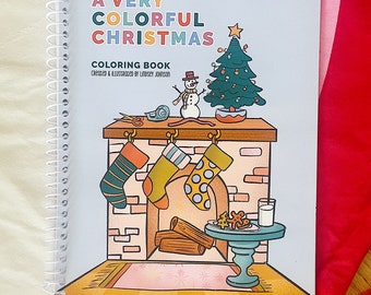 May include: A blue and white coloring book with a spiral binding. The cover features a colorful illustration of a fireplace with stockings, a snowman, and a Christmas tree. The title of the book is "A Very Colorful Christmas Coloring Book" and the text "Created & Illustrated by Lindsey Johnson" is below the title.