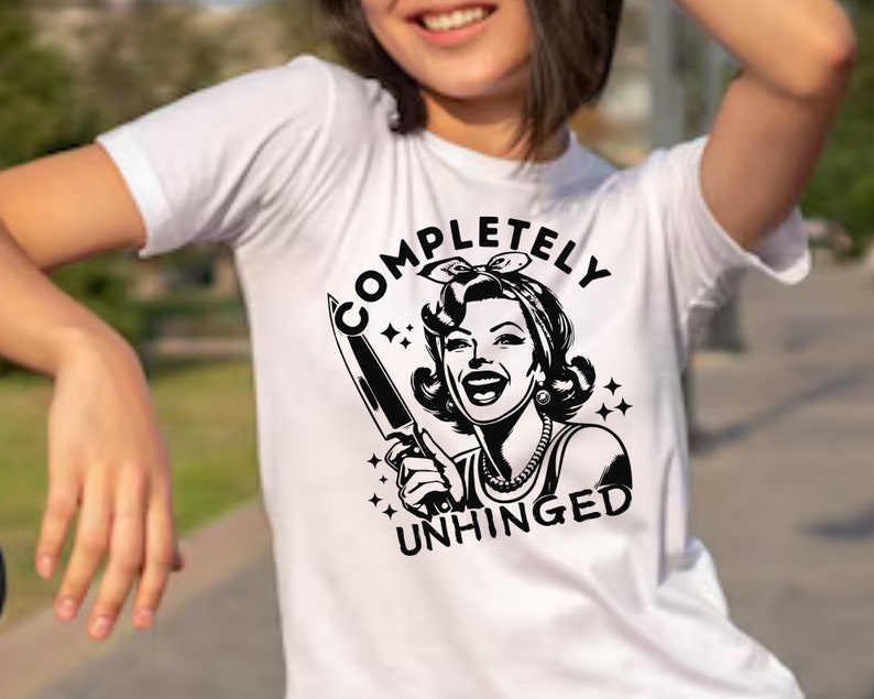 May include: White t-shirt with a black and white illustration of a woman holding a knife and the text "COMPLETELY UNHINGED".