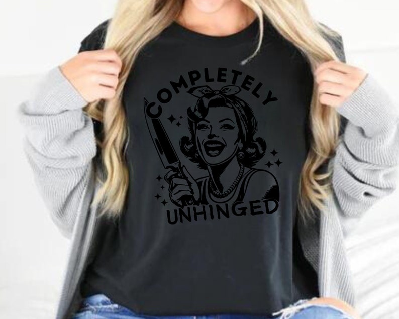 May include: Black t-shirt with a graphic of a woman holding a knife and the text "COMPLETELY UNHINGED".