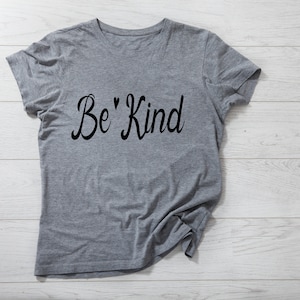 K&ouml;nnte beinhalten: Graues T-Shirt mit dem Text "Be' Kind" in schwarzer Kursivschrift.