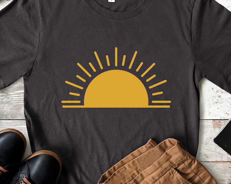 May include: A dark gray t-shirt with a yellow sun graphic. The sun has a simple design with rays extending from the top and bottom.