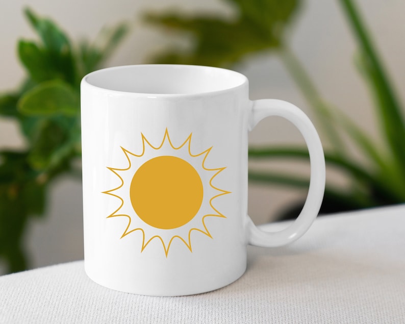 May include: White ceramic mug with a yellow sun graphic. The sun has a yellow center and white rays.