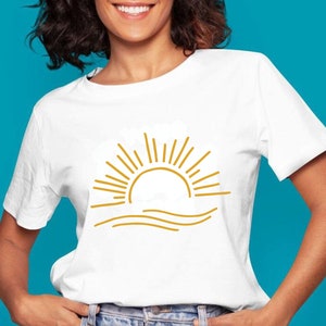 May include: White t-shirt with a gold outline of a sun setting over waves.