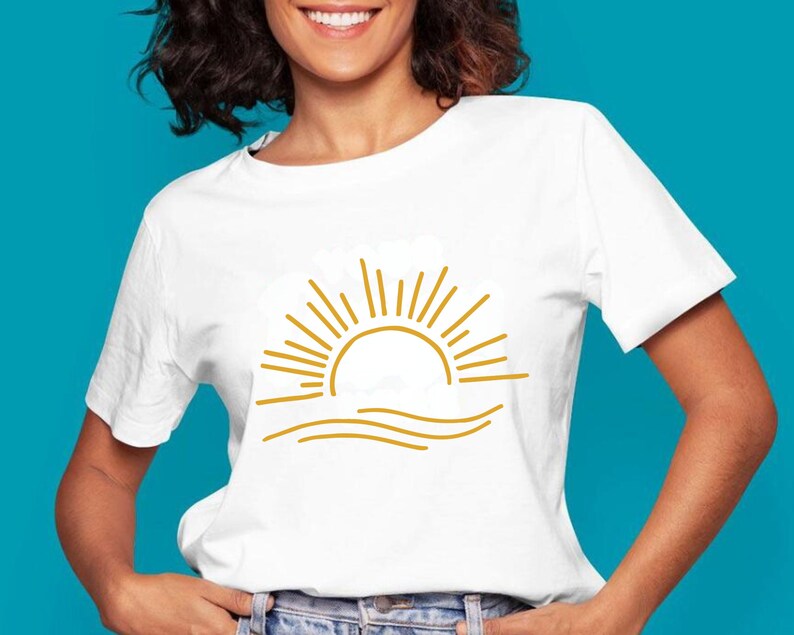 May include: White t-shirt with a gold outline of a sun setting over waves.