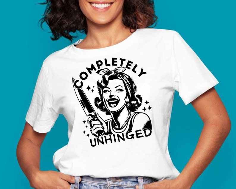 May include: White t-shirt with a black graphic of a woman holding a knife and the text "COMPLETELY UNHINGED".