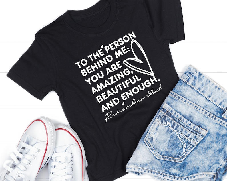 K&ouml;nnte beinhalten: Schwarzes T-Shirt mit wei&szlig;em Text, der lautet: "To the person behind me: You are amazing, beautiful and enough. Remember that."
