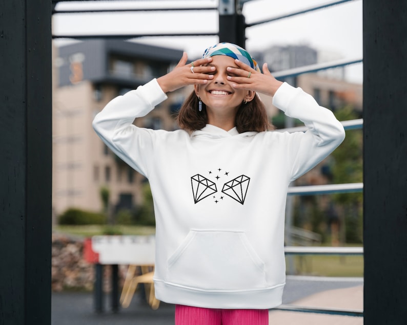 May include: White hoodie with a black diamond graphic and small stars. The hoodie has a drawstring hood and a kangaroo pocket.