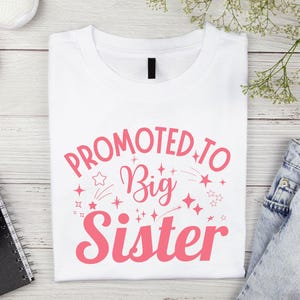 May include: White t-shirt with pink text that reads "Promoted to Big Sister" with stars and shooting stars around the text.
