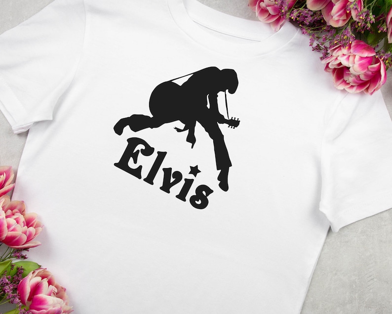 May include: White t-shirt with a black silhouette of Elvis Presley playing a guitar and the word "Elvis" printed below.