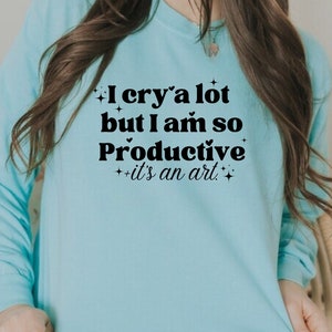 May include: A light blue sweatshirt with the text "I cry a lot but I am so Productive it's an art." printed in black.