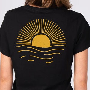 May include: Black t-shirt with a yellow sun setting over the ocean graphic on the back.