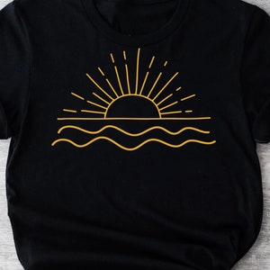 May include: Black t-shirt with a gold outline of a sun setting over wavy water.