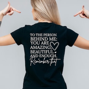 K&ouml;nnte beinhalten: Schwarzes T-Shirt mit wei&szlig;em Text, der lautet: "An die Person hinter mir: Du bist fantastisch, wundersch&ouml;n und genug. Denk daran."