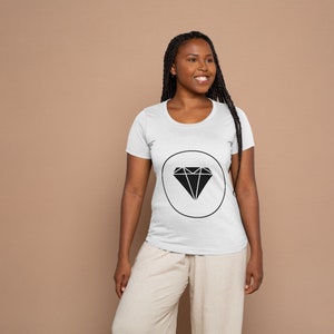 May include: A white t-shirt featuring a black diamond graphic within a circle. The diamond is a geometric shape with multiple points.