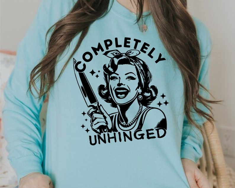 May include: A light blue sweatshirt with a black graphic of a woman holding a knife and the text "COMPLETELY UNHINGED".