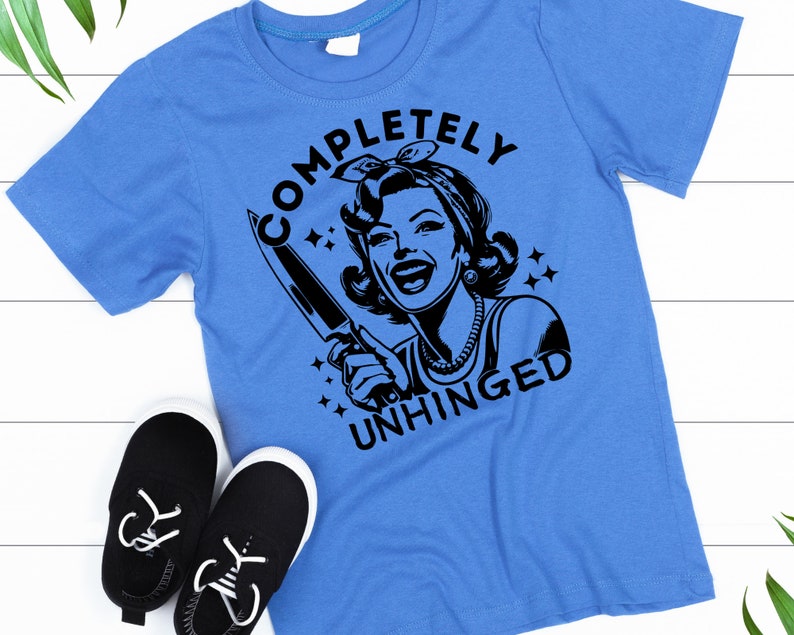 May include: A blue t-shirt with a black graphic of a woman holding a knife and the text "COMPLETELY UNHINGED".