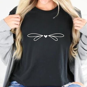 May include: A black t-shirt with a white graphic of a heart with wings.
