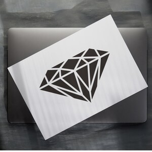 May include: A black diamond shape graphic on a white background. The graphic is on a laptop.