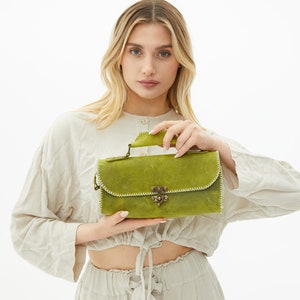 The woman is holding a green leather handbag.