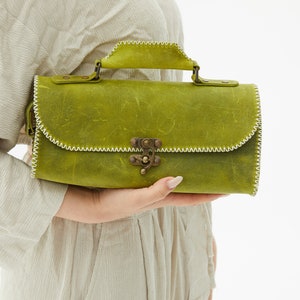 Front view of leather crossbody bag with clip accessory for women.