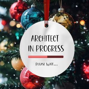 May include: A white Christmas ornament with the text "Architect in progress" and a progress bar that says "Please wait..." hanging on a Christmas tree with red and gold ornaments.
