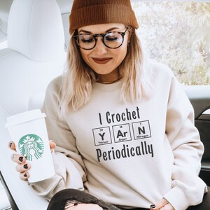 May include: A white sweatshirt with the text "I Crochet Periodically" and a graphic of the chemical elements Yttrium, Argon, and Nitrogen.