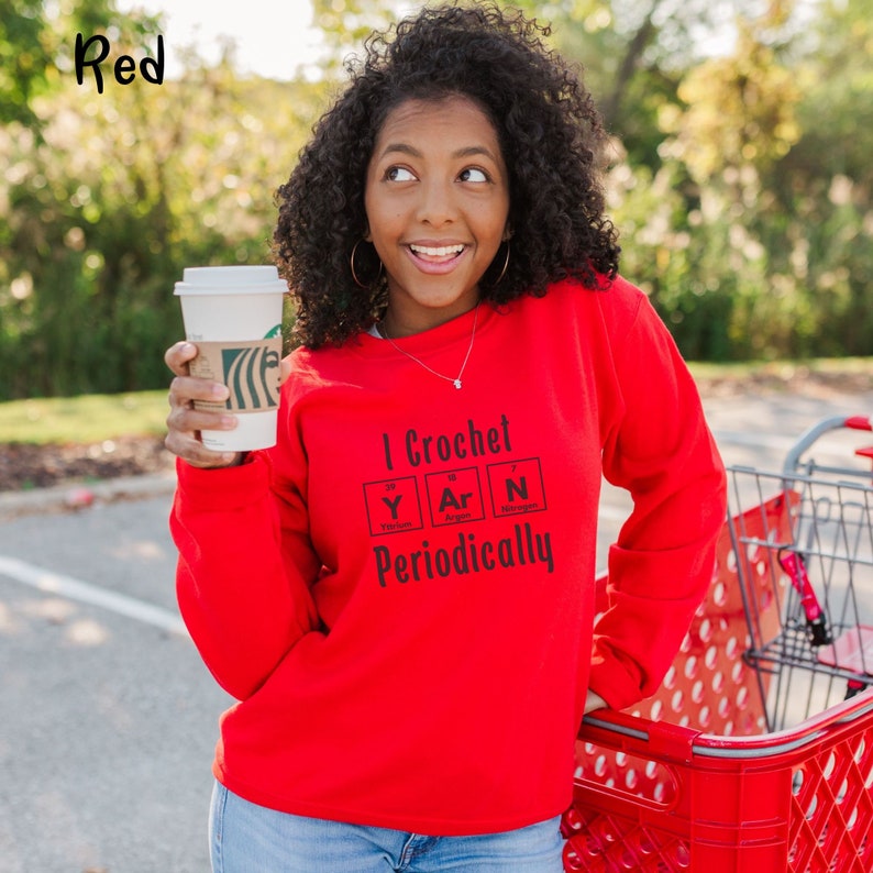 This Funny Crocheting Sweatshirt is a Gildan 18000 crewneck sweatshirt in the color Red. The text on front says I Crochet Yarn Periodically with the word Yarn spelled out in the periodic table.