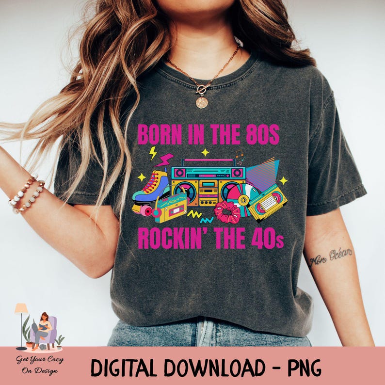 May include: Dark grey t-shirt featuring a colourful 80s-themed graphic. The design includes the text "BORN IN THE 80S ROCKIN' THE 40s" alongside images of roller skates, a boombox, and cassette tapes. The bottom of the shirt says "DIGITAL DOWNLOAD - PNG".