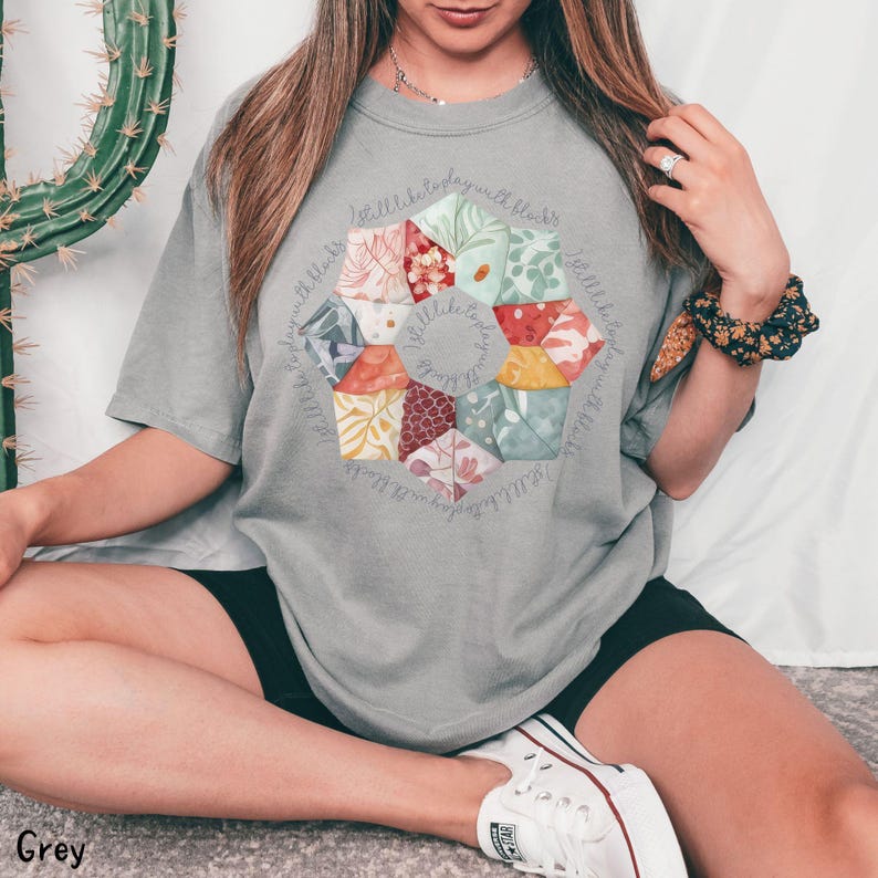 May include: A grey t-shirt with a floral design and the text "Little bits of joy with little bits of love" around the design.