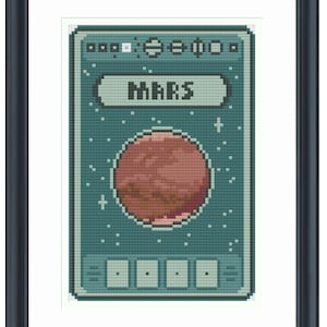 May include: Framed cross-stitch art featuring a pixelated design of Mars. The artwork showcases a red planet with a textured surface, set against a teal background with the word "MARS" in a banner. The piece is framed in a black, rectangular frame.