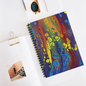 May include: Abstract spiral notebook with a colorful, swirling design featuring blue, yellow, orange, and red paint. The design resembles a galaxy or a nebula.