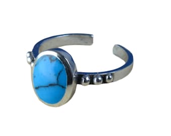 May include: A silver ring with a turquoise stone set in a bezel setting. The ring has a beaded band.